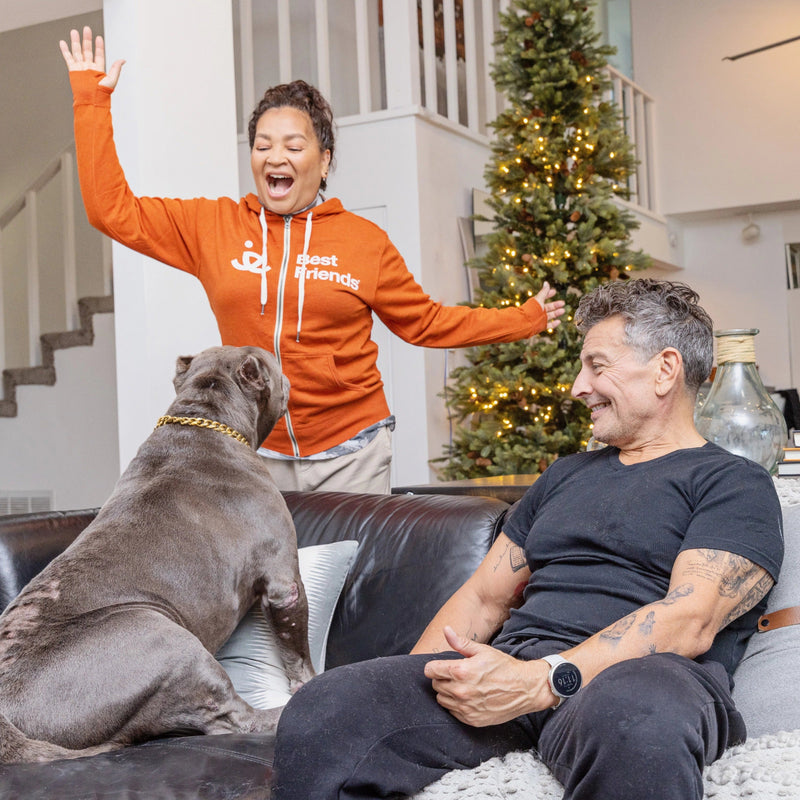 Woman wearing a Best Friends Animal Society sweatshirt waving to a dog